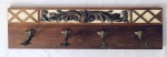 Cabideiro em madeira decorado com entalhe, contendo quatro ganchos em metal. Med. 79x22 cm.