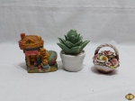 Lote composto de 3 enfeites, sendo 2 em arranjos em porcelana e casa na forma de sapato em resina. Medindo o arranjo maior 11,5cm de altura.