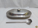 Legumeira oval com tampa e colher em aço inox Tramontina. Medindo 30,5cm x 21cm x 3,5cm de altura sem a tampa.