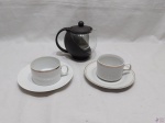 Bule com coador em vidro incolor e  2 xícaras de chá em porcelana com friso ouro. Medindo o bule 11cm de altura.