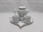Jogo com 4 peças em porcelana Schmidt para bodas de prata, composto de bule, 2 xícaras de café e 1 bandeja na forma de coração.
