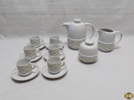 Jogo de servir café com 9 peças em porcelana Pozzani, composto de bule, leiteira, açucareiro e 6 xícaras com pires. Medindo o bule 13cm de altura sem a tampa.