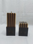 Par de velas decorativas com castiçais em metal com hieróglifos orientais. Medindo a vela maior 20cm de altura.