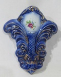 PORCELANA - Uma floreira de parede em porcelana vitrificada branca, com esmaltagem na tonalidade azul, decorada com motivos vegetalistas e arremates em douração. Medidas alt 18 cm x larg 15 cm.