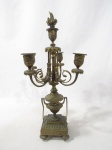 CANDELABRO/ CASTIÇAL - Belíssimo candelabro para cinco velas, confeccionado em bronze, ricamente trabalhado com cinzelado em relevo, com quatro braços fixos em forma de volutas, coluna em formato balaústre, seguido de base quadrada, sobre quatro pés ligeiramente obcônicos. Medidas alt 45 cm x comp da base 9,5 cm x larg da base 9,5 cm. Acompanha apagador de velas. Possui uma pequena morsa na base.