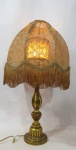 ABAJUR - Um (1) abajur de mesa com base em madeira trabalhada com folha de ouro, cúpula em renda francesa  decorado com franja. Medidas: altura total 67 cm x base 13,5 cm tecido da cúpula amarelado pela ação do tempo - funcionando, mais sem garantia futuras. possui rasgado na parte interna.