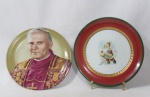 PORCELANA - Dois pratos decorativos em porcelana vitrificada e policromada, sendo um fabricado na França apresentando imagem do Papa Joao Paulo II (marcado no fundo), e um pintado à mão, decorado com tema natalino (Papai Noel com presentes - assinado Rosa Maria). Medidas: maior 25,5 cm de diâmetro/ menor: 24,5 cm de diâmetro..