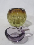 MURANO - Um vaso com bojo gomado e um cinzeiro em formato de maçã, confeccionados em murano nas cores âmbar e lilás, respectivamente. Medidas: vaso: alt 11 cm/ diam da borda 10 cm/ cinzeiro: alt 4 cm larg 9 cm.