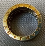 JOIA, uma (1) aliança marcada BULGARI, confeccionada em metal nobre não identificado, duro, não desaparece com o ácido, possivelmente ródio ou platina, tamanho 20, peso aproximado 9,7 gr, puncionado na parte interna BULGARI 750 A0521V.