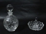 CRISTAIS - Um perfumeiro e uma aneleira em cristal translúcido europeu, com profusa lapidação de motivos geométricos e sulcos, tampa em formato esférico e bordas onduladas. Medidas: maior 13 cm de altura/ menor: 6 cm de altura.