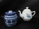 DUAS PEÇAS - Um bule em porcelana branca vitrificada, bojo com gomos e flores filetados a ouro, marcado no fundo: Medidas: 16 cm de altura: 12 cm de largura. B) um pote em porcelana Monte Sião nas cores azul e branca, bojo de corado co caneluras, tampa decorada com gomos. medidas: 16 x 12 cm. (marcado no fundo.