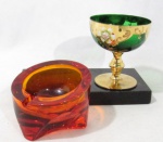 DIVERSOS - MURANO/ CRISTAIS - Lote contendo duas peças, sendo A: um elegante cinzeiro em murano na cor laranja, medindo: 7,5 cm de altura; 10 cm de diâmetro;B: uma taça em cristal verde, decorada com pintura veneziana com vasta douração e  flores policromadas, haste trabalhada com expansão intermediária, seguido de base circular, medindo: altura 10 cm x diâmetro 9,5 cm.