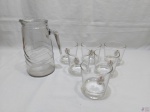 Lote composto de jarra em vidro moldado com 6 copos em vidro com base pesada. Medindo a jarra 22cm de altura.