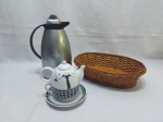 Lote composto de xícara de chá com bule acoplado em porcelana, pãozeira em ratam e garrafa térmica. Medindo a pãozeira 32cm x 22cm x 9cm de altura.