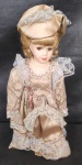 Antiga boneca de coleção de porcelana, veste bege rendada, olhos castanhos. Alt. 32cm
