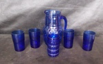 Jarra com 5 copos de vidro no padrão azul cobalto, sendo a jarra e um copo com decoração geométrica e 4 copos liso. Alt jarra 22cm alt copo 11cm