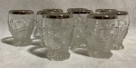 Lote com 9 copos de vidro lapidação em paralelas ascendentes e descendentes, base acidada e com bordas com filetes de prata. Alt. 6 cm