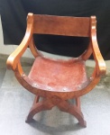 Antiga cadeira SAVONAROLA em madeira nobre com entalhes florais na parte frontal, acento e encosto em couro e apliques em metal, medindo: frente: 57cm/ altura: 84cm/ profundidade 52cm.