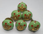 Meia dúzia de puxadores em porcelana na cor verde com pintas em vermelho e miolo dourado, medindo 4cm.