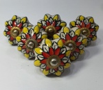 Meia dúzia de puxadores em porcelana no formato de flor pintado à mão nas cores branca, amarela e vermelha com miolo dourado, sendo três pares , medindo 4cm de diâmetro.