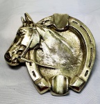 Belíssimo cinzeiro  em pesado bronze polido no formato de ferradura com cabeça de cavalo, medindo 12,5cmX 12cm.