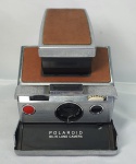 Raridade - A Polaroid SX-700 Land Camera, lançada em 1972 e fabricada nos EUA, foi a primeira (e única) câmera reflex da marca e surpreendeu pelo design arrojado. Até hoje é um objeto cultuado (e ainda usado) por uma legião de fãs. A fotografia instantânea, como a revelação da imagem ocorrendo logo depois do clique, foi inventada pelo engenheiro americano Edwin H. Land depois de se incomodar com uma pergunta da filha, que tornou célebre: papai, por que não 0posso ver a foto agora?. O problema foi resolvido em 1948. Acompanha case original, máquina não testada,  vendida no estado.