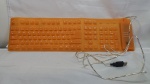 Teclado em silicone laranja com fio, funcionando, medindo 13,5cm X 49cm.