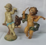 Par de antigas e pequenas estatuetas em resina sendo um menino alimentando um esquilo medindo 11cm e um anjo tocando violino medindo 11cm.