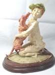 Bela escultura em resina italiana com base em madeira representando um menino e seu cão ricamente detalhada, medindo 21cm de altura e 14cmX20cm de base.