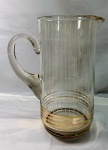Bela e antiga jarra em vidro da década de 60 com listas verticais em branco e listas horizontais em dourado, medindo 24,5cmX11,5cm.