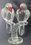 Belíssima escultura lapidada em pesado  cristal no formato de um casal de papagaio pousados em um galho, ricamente detalhada , bico vermelho e olhos amarelos, medindo  25cm de altura, 17cm de largura por 10cm de profundidade.