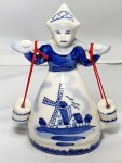 Souvenir- Pequeno Souvenir representando uma Holandesa carregando potes com água em porcelana branca com desenhos típicos Holandês na cor azul cobalto, medindo 9,5cm de altura.