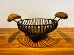 Fruteira de ferro com alça de madeira formato de banana e fundo de madeira. Medidas: comprimento 44 x diâmetro 31 cm.