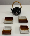 Quatro recipientes para molho shoyu e uma chaleira japonesa.