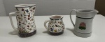 Três jarras sendo duas em cerâmica pintada a mão e uma em porcelana inglesa - altura da maior 19 cm.