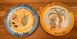 Pratos de cerâmica da Boa Lembrança pintados a mão, sendo um do Pato com Laranja Rio 2001 e um O Navegador Rio 99 - Diâmetro: 27 cm