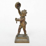 Escultura em bronze representando PUTTO tocando pandeiro. Primeira metade do século XX. Medida: 13,5 cm de altura x 5cm de comprimento x 4,5cm de profundidade.