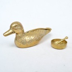 Extraordinário quebra nozes em formato de pato em metal dourado. Medida: 10cm de altura x 7cm de comprimento x 23cm de profundidade. Pequena cumbuca em metal dourado bastão. Medida: 2cm de altura x 6cm de diâmetro. Medida do bastão 7cm.