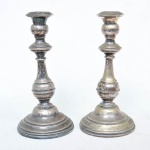 Par de castiçal em metal prateado. Medida: 22cm x 11cm. OBS: um possui o suporte da base solta. Necessita limpeza.