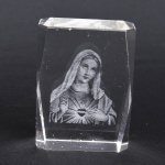 Bloco/peso em cristal com gravação interna representando figura de Nossa Senhora. Medida: 8cm x 6cm x 3cm.