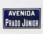 Placa esmaltada em ágata para identificação de rua com inscrição "AVENIDA PRADO JÚNIOR". 25cm x 45cm.