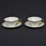 REAL - Par de xícaras de chá em porcelana  nacional com detalhes dourados  e alça dourada. Uma com inscrição "ELA" e "EU". Marca de sua manufatura em sua base. Medida: 10 cm x 6 cm; Pires: 15 cm de diâmetro.