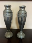 Par de vasos em metal prateado com borda decorada por flores em relevo. Medida: 31cm de altura x 9cm. x 9,5m de diâmetro a base.