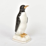 Escultura representando pinguim com pés dourado. Medida: 23cm x 9cm.