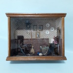 MINIATURA - Sala em miniatura decorada com cadeira de balanço, relógio de parede e cômoda. Emoldurada e com vidro de proteção. Dimensões: 19 cm x 24 cm x 9cm.