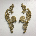 Antigo par de adornos em bronze revestido de dourado ricamente ornado por arabescos e volutas. Dimensões: 23 cm comprimento.