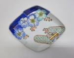 Gracioso covilhete em porcelana oriental em formato de losango. Peça esmaltada com flores em policromia e realçado a ouro. Medidas: 18 X 15 cm.