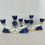 PORCELANA SANTA TEREZINHA - Par de candelabros em porcelana nas cores branca e azul, decorado com flores e frisos dourados, med. 29cm de cumprimento, 17,5cm de altura. 