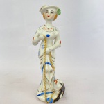 Estatueta em porcelana na cor branca com policromia e frisos prateados representando mulher com cachorro, med. 25cm de altura 