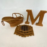 Lote com 3 (três) peças, sendo:  Porta garrafa em palha manufatura SCHULZ, med. 29cm e conj. de descanso para panela em madeira, med. maior 20X19cm e enfeite em alumínio com lâmina de madeira com a letra `M`, med. 19X24cm   